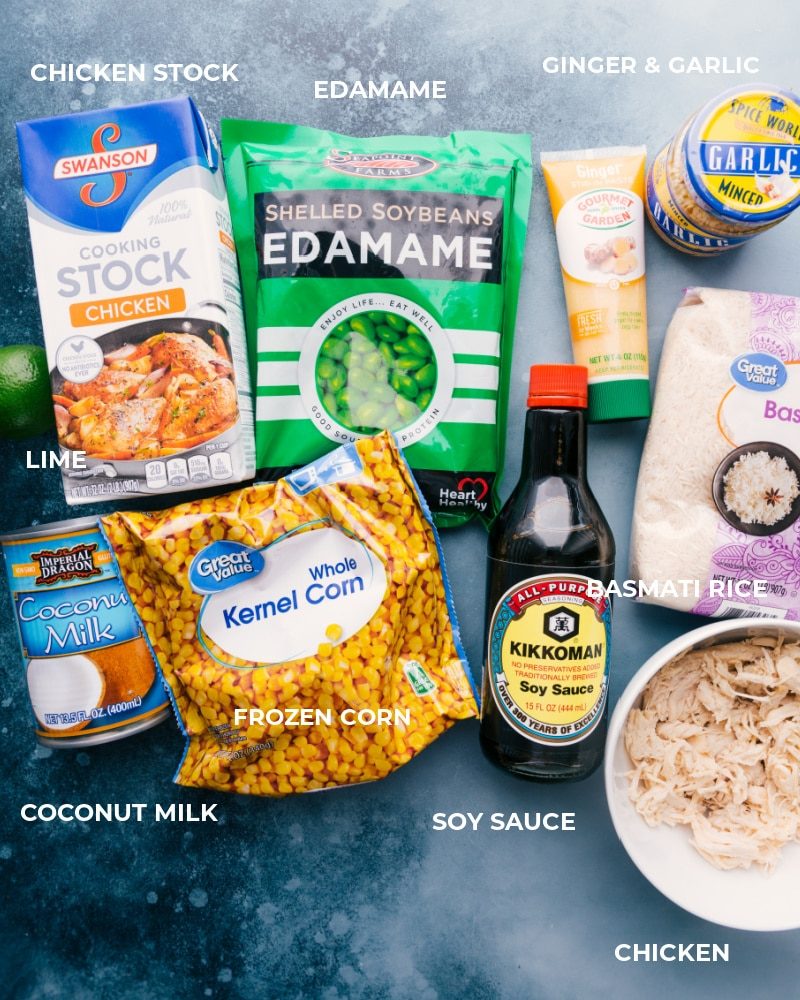 Assembled ingredients, including chicken stock, edamame, ginger, garlic, lime, coconut milk, frozen corn, soy sauce, basmati rice, and cooked chicken.