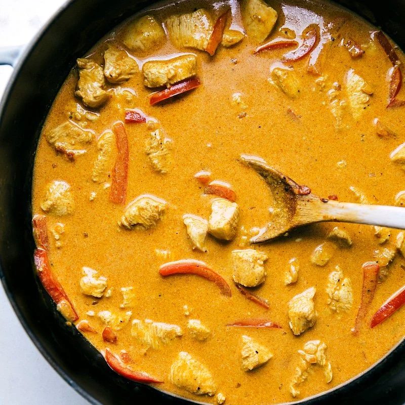 The flavorful meal cooking in the pan, rich with sauce and aromatic spices.