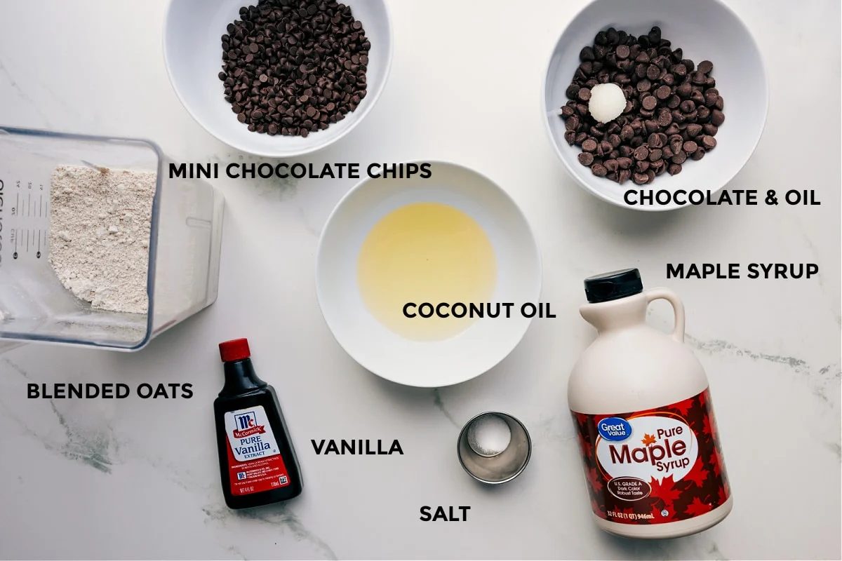 All the ingredients for this recipe are prepped and ready for straightforward assembly, including chocolate, coconut oil, maple syrup, vanilla, salt, and oats.
