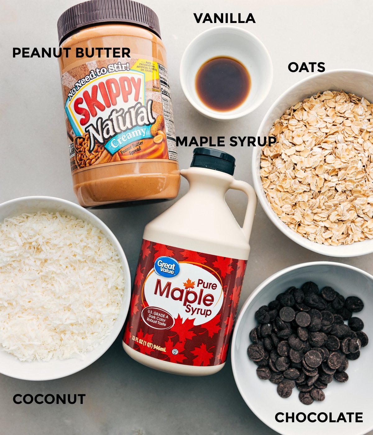 All the ingredients in this recipe, including peanut butter, vanilla, oats, maple syrup, coconut, and chocolate, are prepped for straightforward assembly.