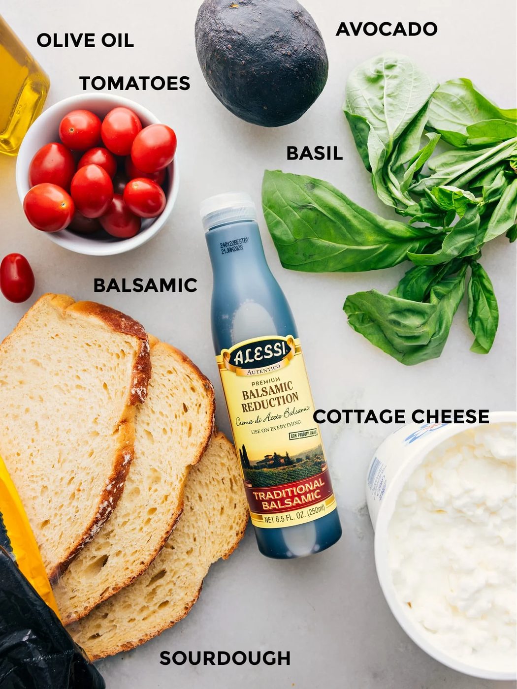 All the ingredients used in this recipe including sourdough, cottage cheese, tomatoes, olive oil, avocado, basil, and balsamic reduction prepped out for straightforward assembly.