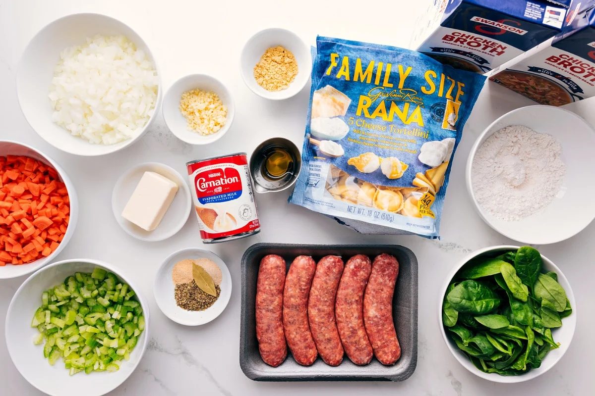 All the ingredients in this recipe prepped out for straightforward assembly including the veggies, butter, seasonings, evaporated milk, garlic, tortellini, sausage, flour, and chicken broth.