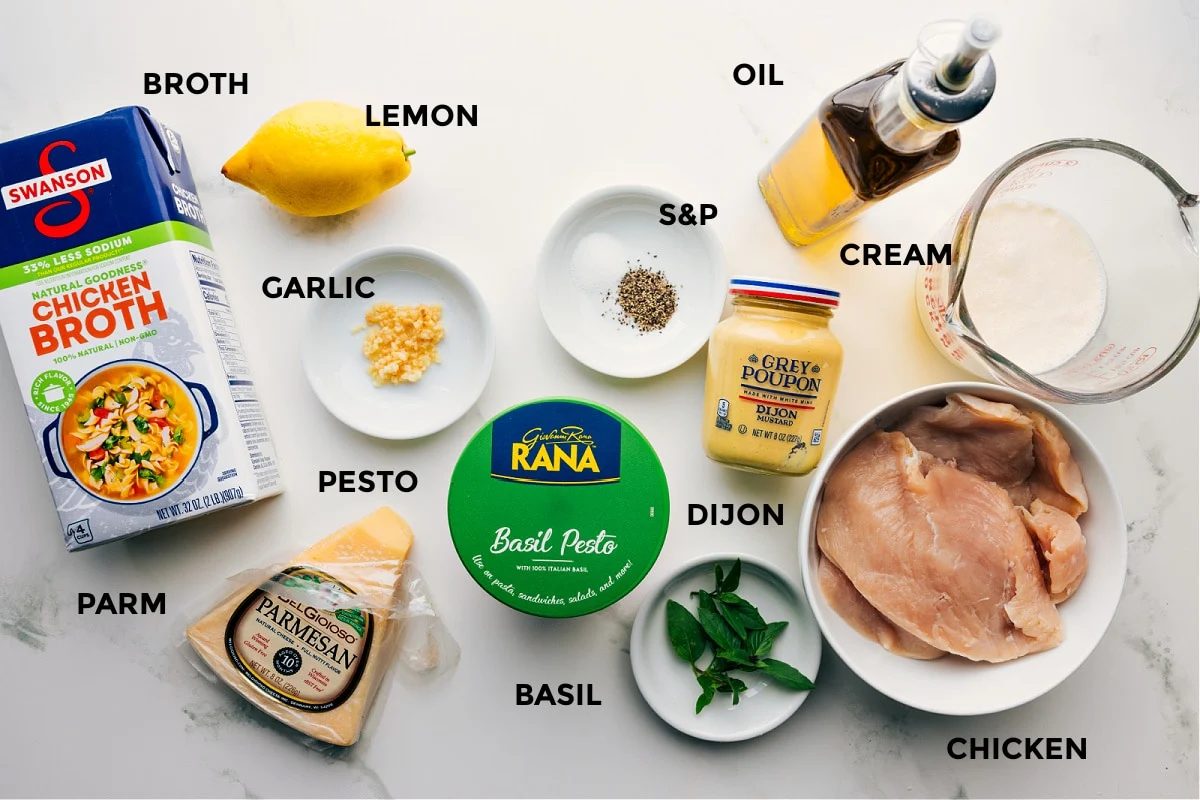 All the ingredients in this recipe prepped out for straightforward assembly including the broth, lemon, garlic, pesto, basil, basil, dijon, chicken, cream, and oil.