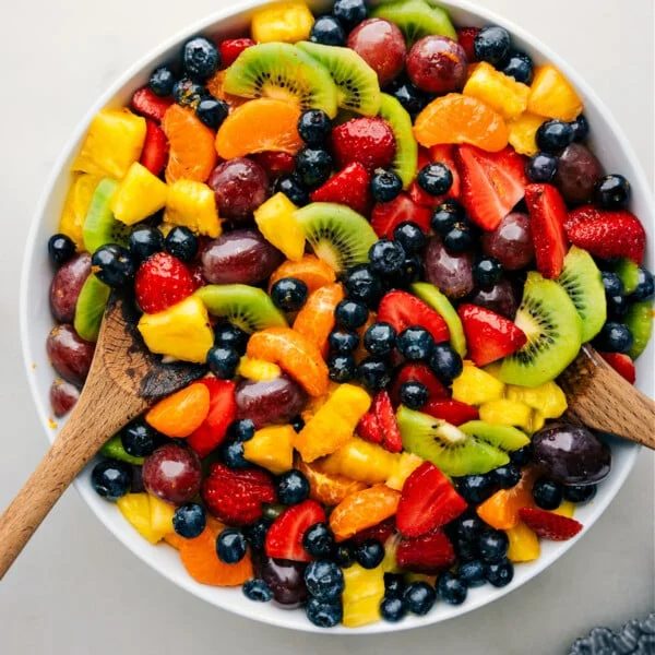 The straightforward fruit salad recipe in a bowl with serving spoons.