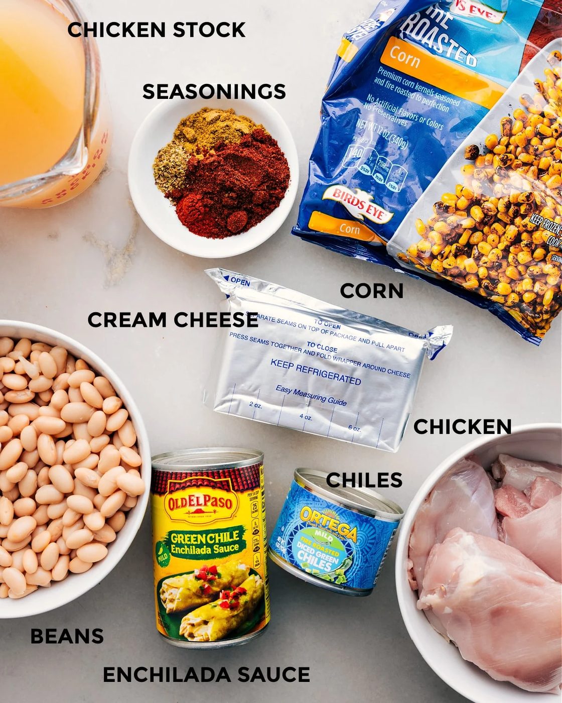 Prep all the ingredients for this recipe, including stock, seasonings, corn, cream cheese, meat, chiles, beans, and enchilada sauce, for straightforward assembly.