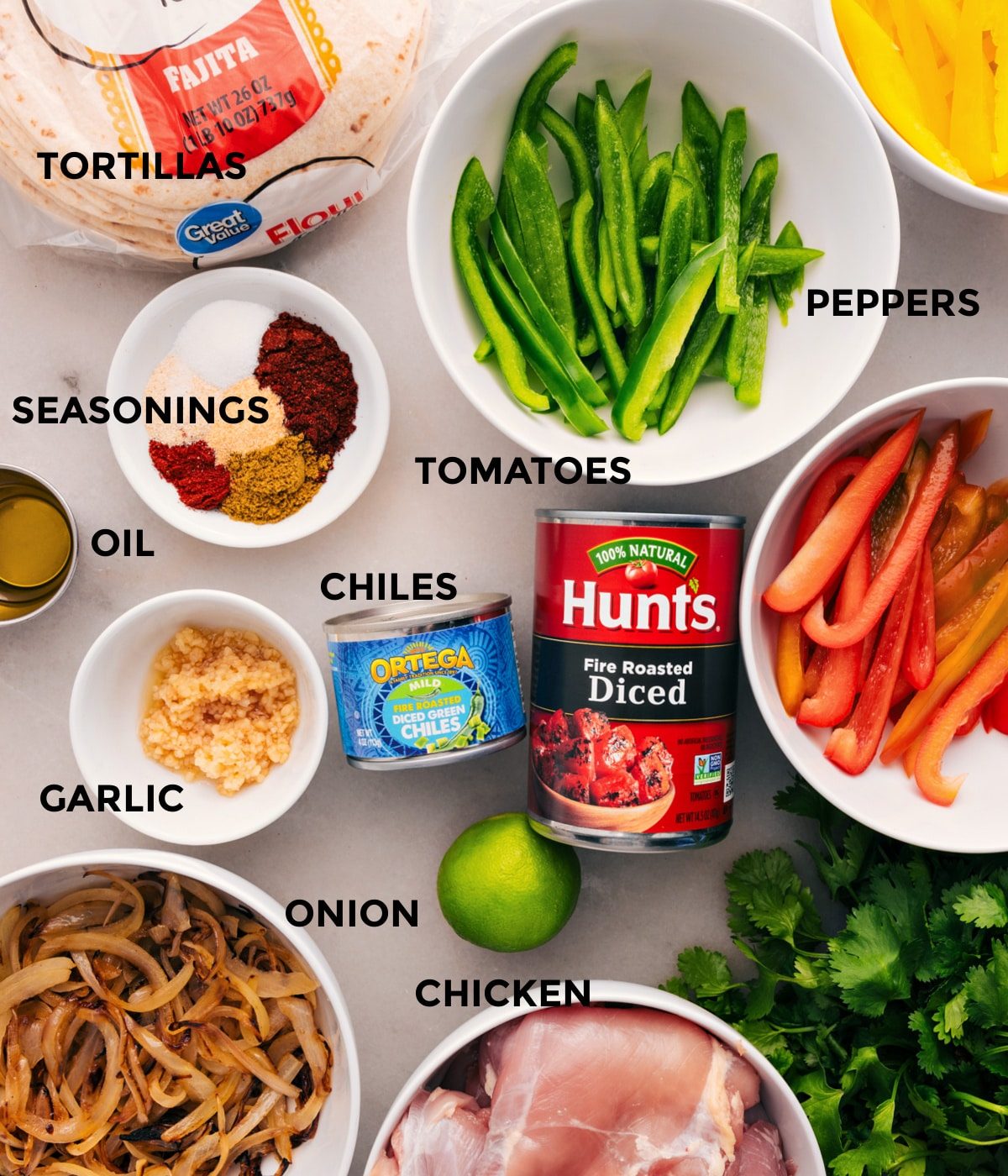 All the ingredients for this dish are prepped for straightforward assembly: peppers, meat, tomatoes, chiles, garlic, seasonings, tortillas, onions, and limes.