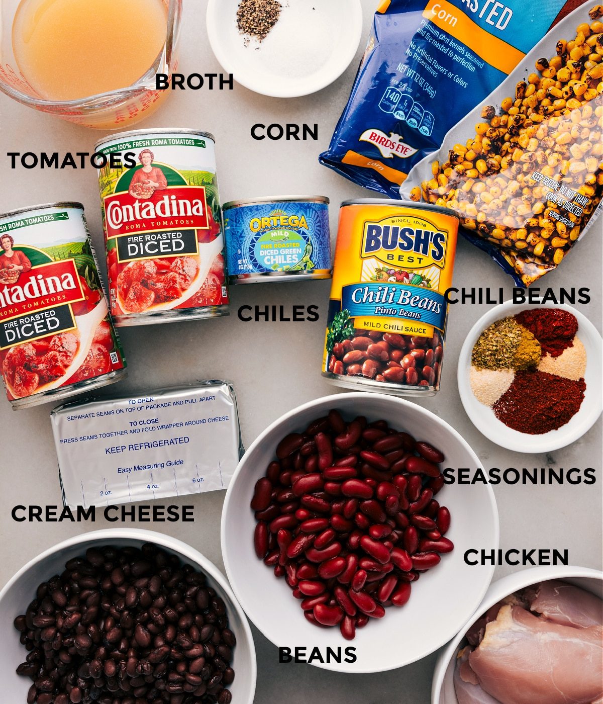 Ingredients like broth, seasonings, corn, beans, tomatoes, chiles, cream cheese, and meat prepped and ready for straightforward assembly.