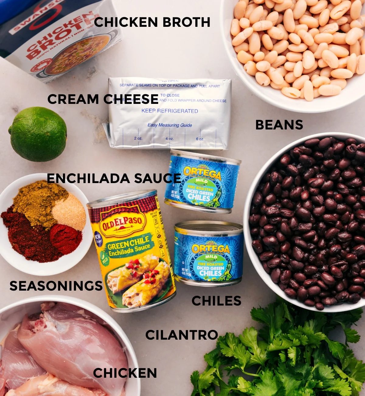 This recipe's ingredients are prepped for straightforward assembly: beans, meat, chiles, sauce, seasonings, cream cheese, lime, and cilantro.