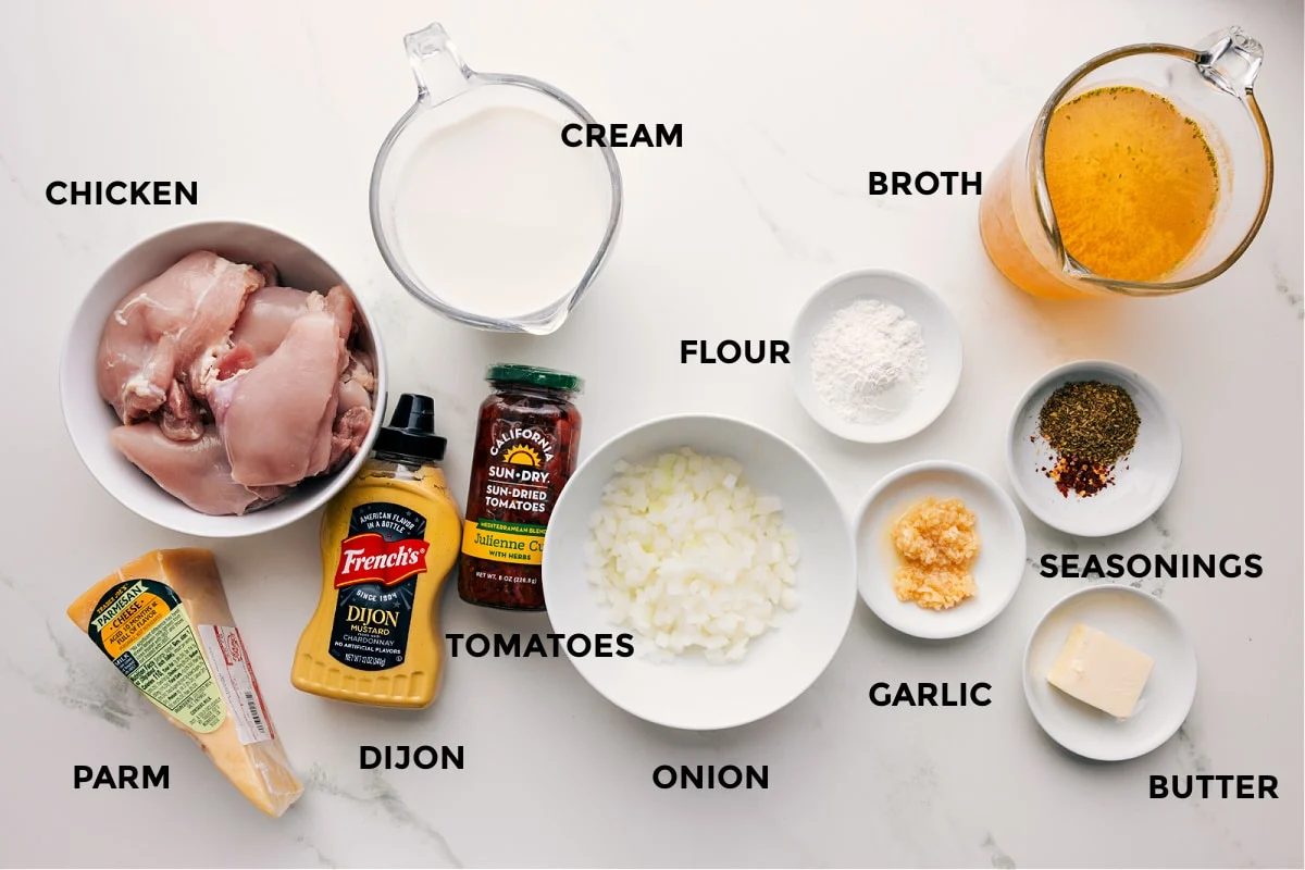 All the ingredients prepped for straightforward assembly, including chicken, Parmesan, Dijon, cream, tomatoes, onion, flour, garlic, seasonings, butter, and broth.