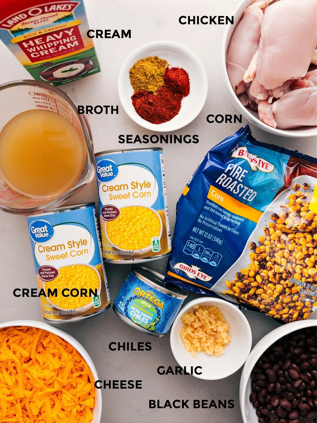 All the ingredients—broth, seasonings, meat, veggies, black beans, chiles, and cheese—are prepped for straightforward assembly.