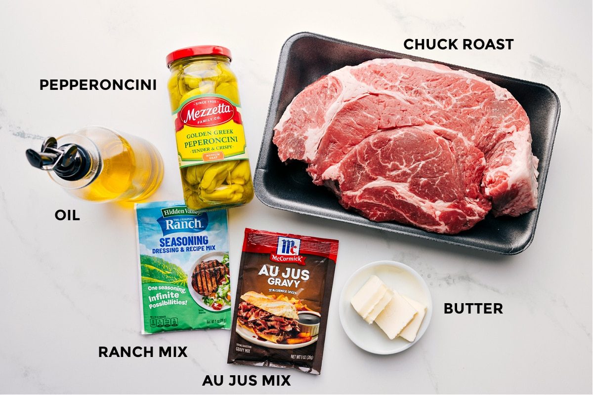 Ingredients prepped for straightforward assembly: pepperoncini, chuck roast, ranch mix, au jus mix, butter, and oil.