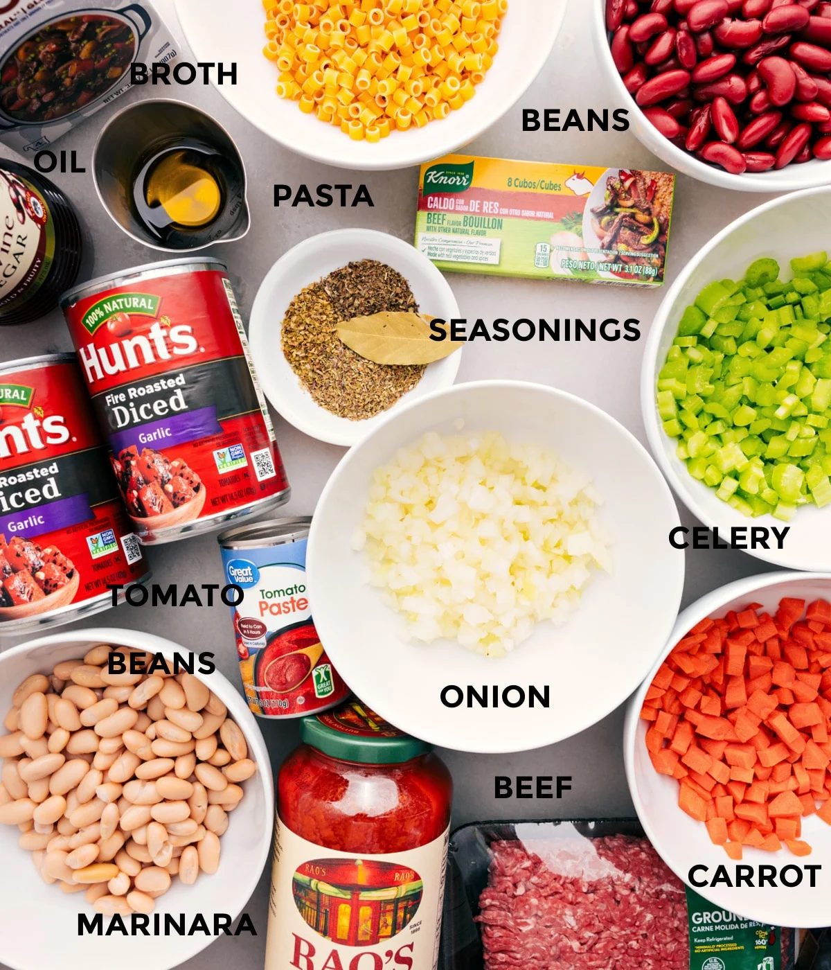 All the ingredients for this recipe are prepped and ready for straightforward assembly—veggies, beans, tomatoes, pasta, seasonings, oil, broth, beef, and marinara sauce.