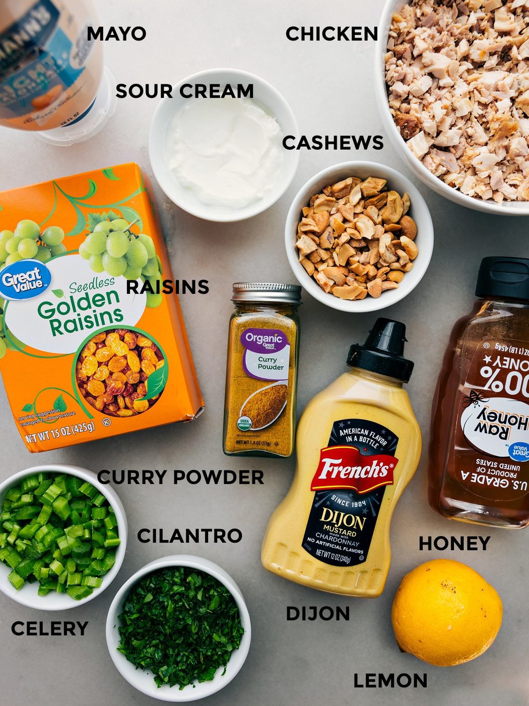 All the ingredients prepped out for straightforward assembly, including mayo, sour cream, chicken, cashews, raisins, cilantro, celery, dijon, honey, and lemon.
