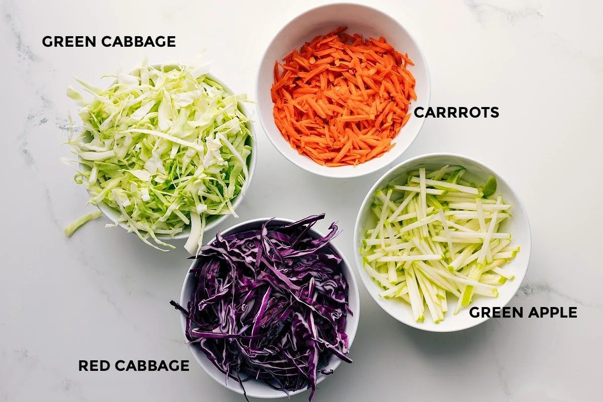 The ingredients in this recipe prepped out for straightforward assembly including the green cabbage, red cabbage, carrots, and green apple.