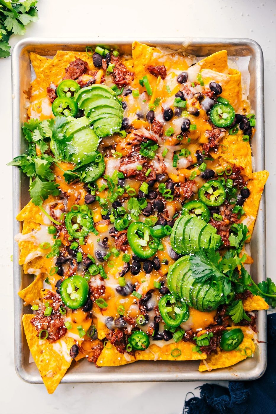 Loaded pulled pork nachos topped with melted cheese, barbecue sauce, and fresh toppings.