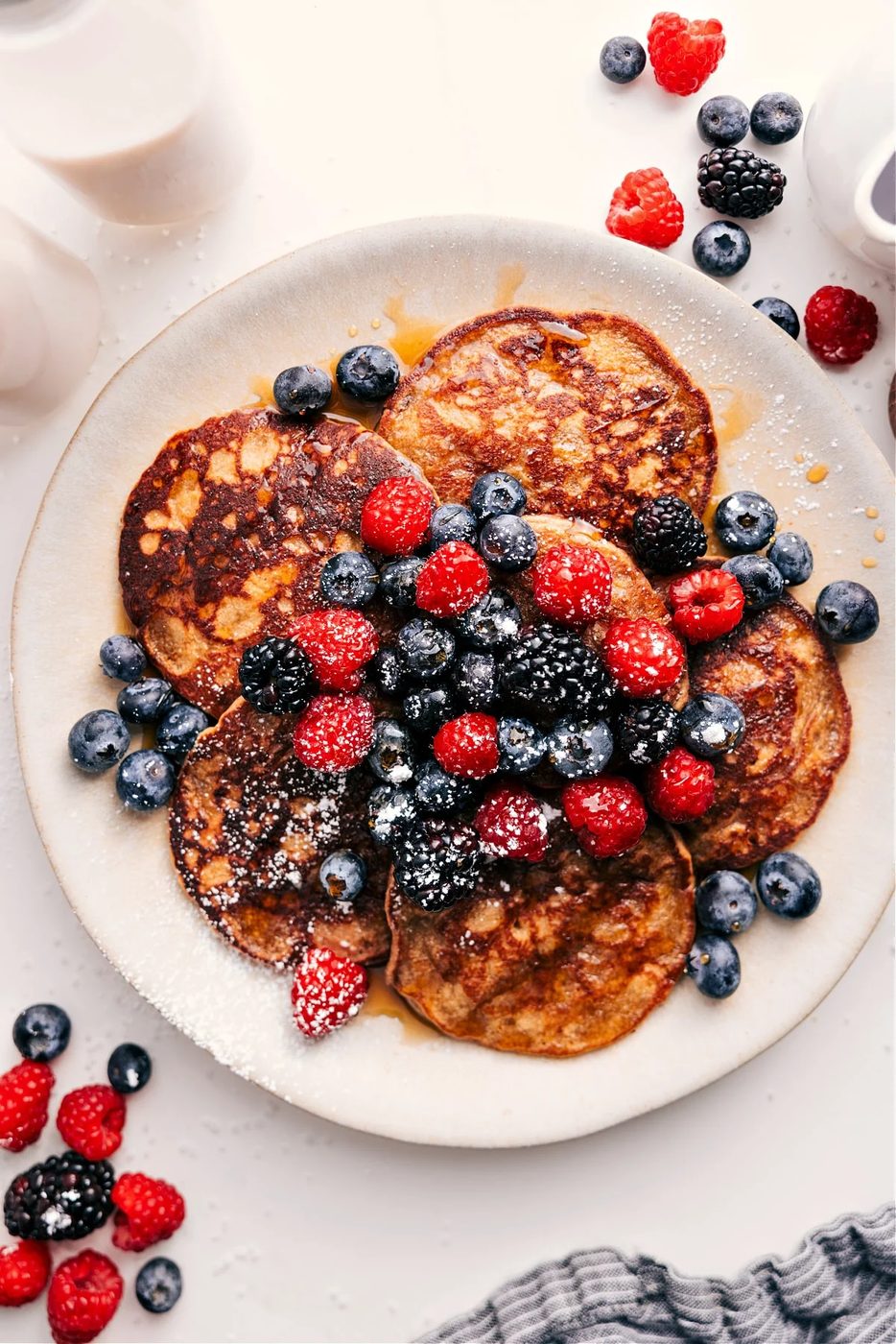 Fluffy healthy pancakes with golden edges served with fresh berries and maple syrup.