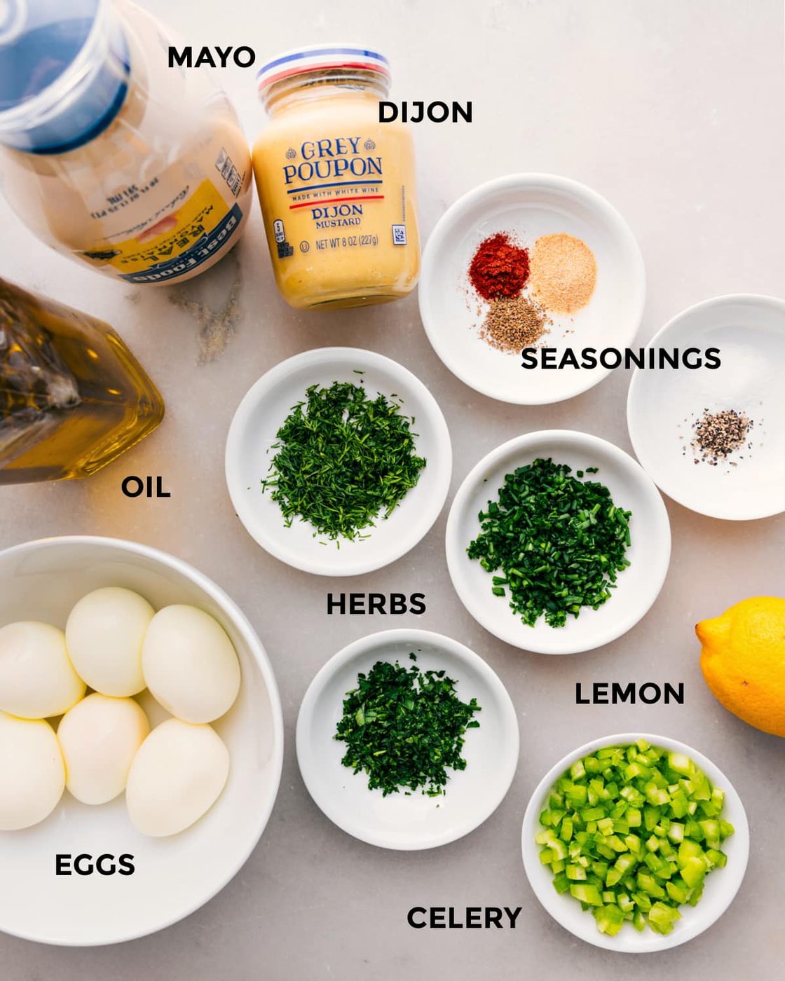 All the ingredients prepped for straightforward assembly, including mayo, dijon, seasonings, herbs, oil, eggs, lemon, and celery.