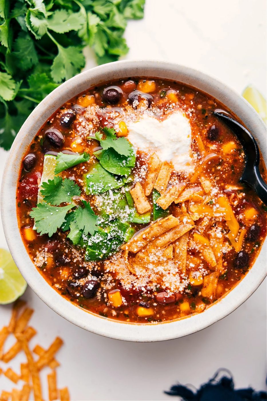 Chicken taco soup with shredded chicken, beans, corn, and toppings like cheese and avocado.