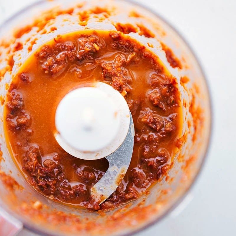 Blending the sun-dried tomato sauce in a food processor, capturing the ingredients coming together to create a flavorful sauce for this flat iron steak recipe.