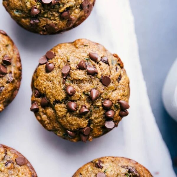 Gluten free zucchini muffins freshly out of the oven, topped with mini chocolate chips, ready to be enjoyed as a satisfying breakfast or snack.