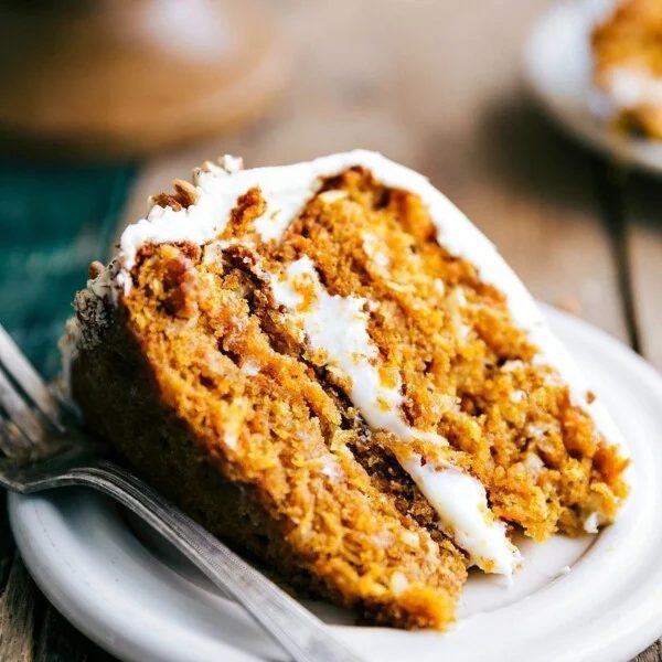 Slice of pumpkin carrot cake revealing its soft and moist interior, topped with a satisfying icing.