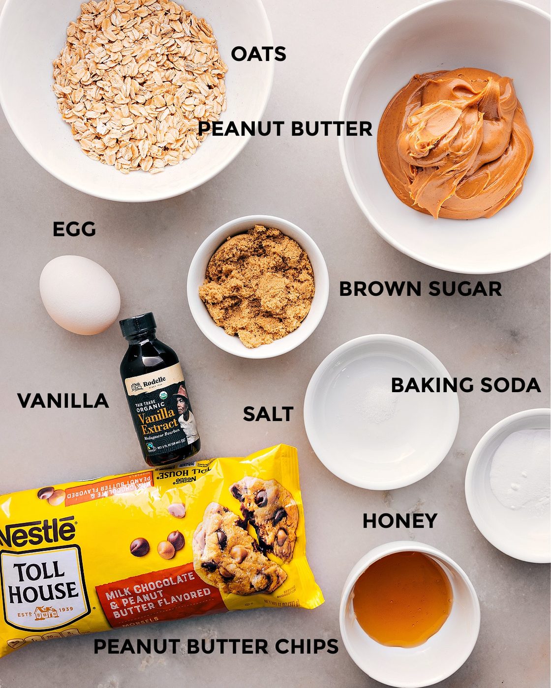 All the ingredients prepped for straightforward assembly, including oats, peanut butter, sugar, baking soda, salt, vanilla, honey, and peanut butter chips.