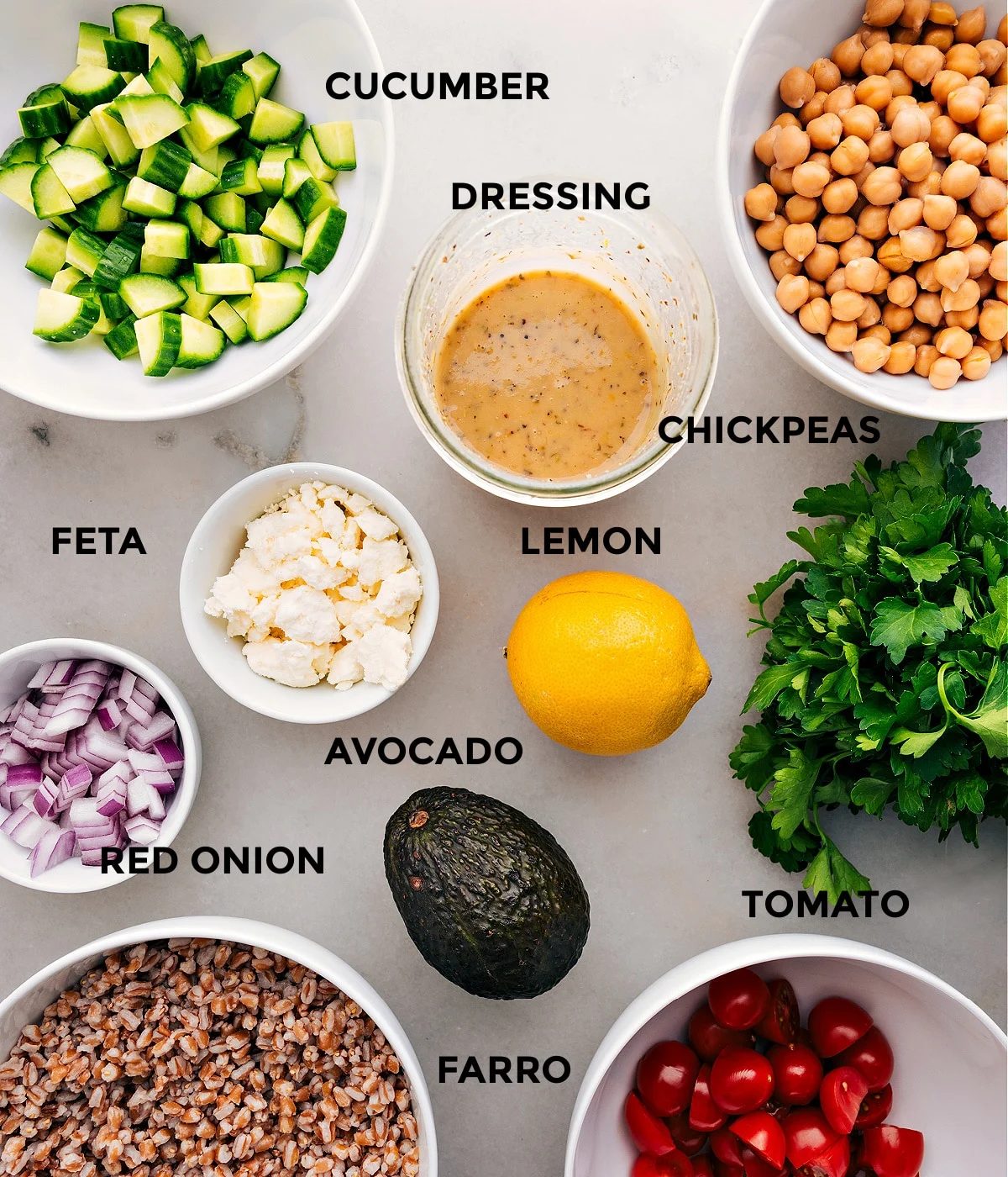 This recipe includes prepped ingredients like dressing, chickpeas, veggies, feta, lemon, farro, and parsley for straightforward assembly.