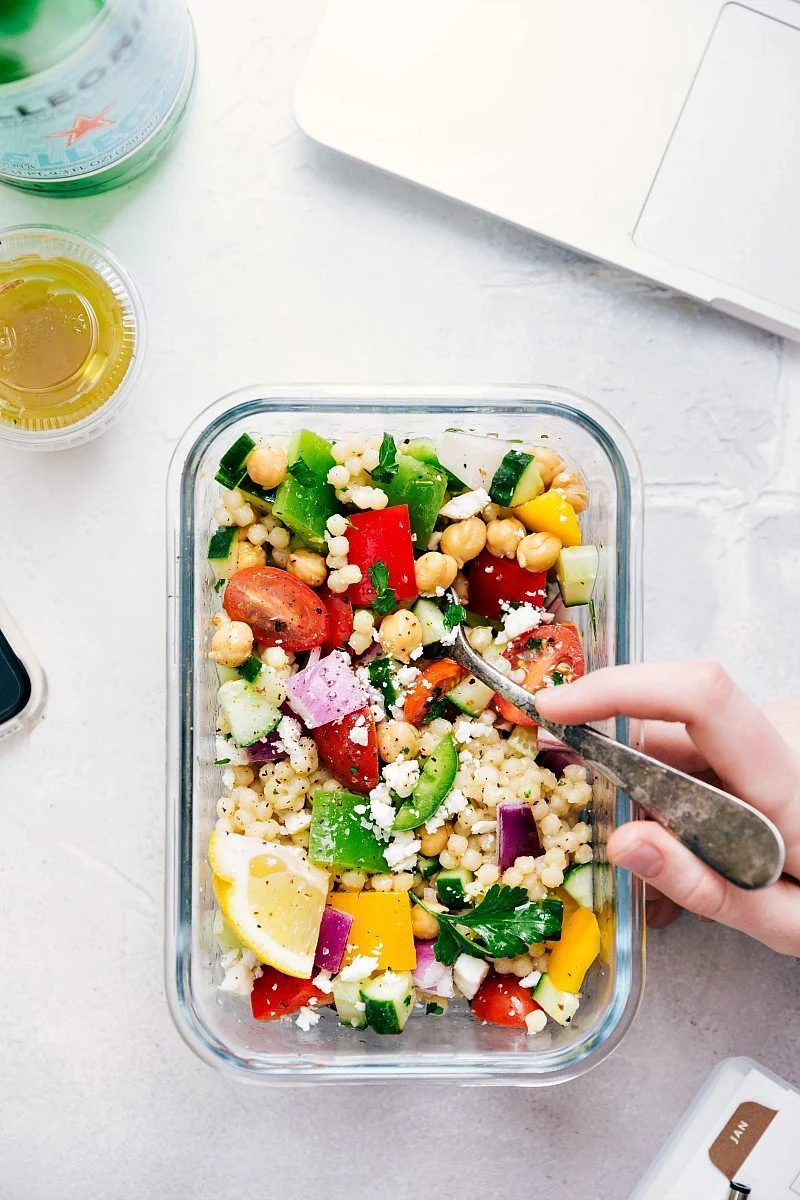 Greek couscous salad in a meal prep container ready to be enjoyed.