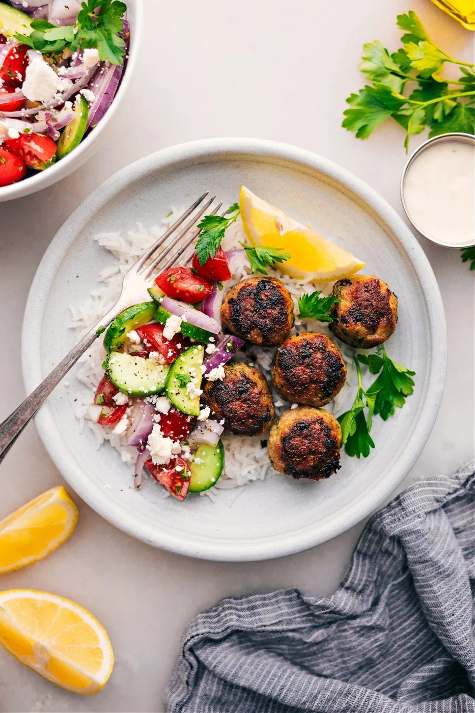 Greek turkey meatballs over rice with a cucumber tomato salad on the side.