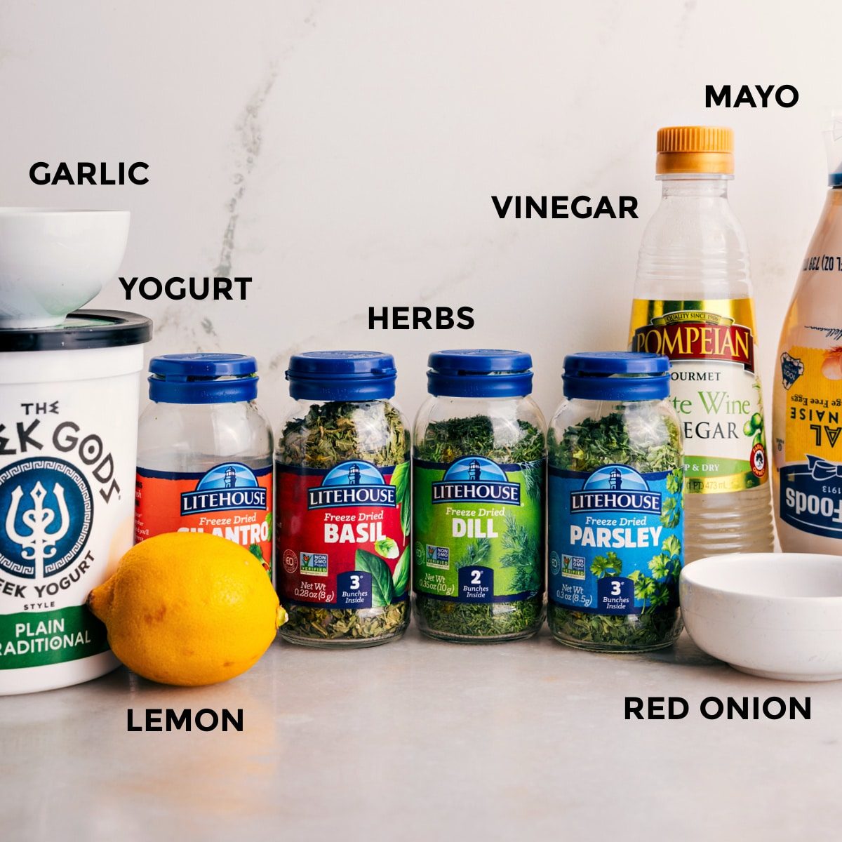 All the ingredients for this recipe are prepped and ready for straightforward assembly: mayo, vinegar, herbs, yogurt, and garlic.