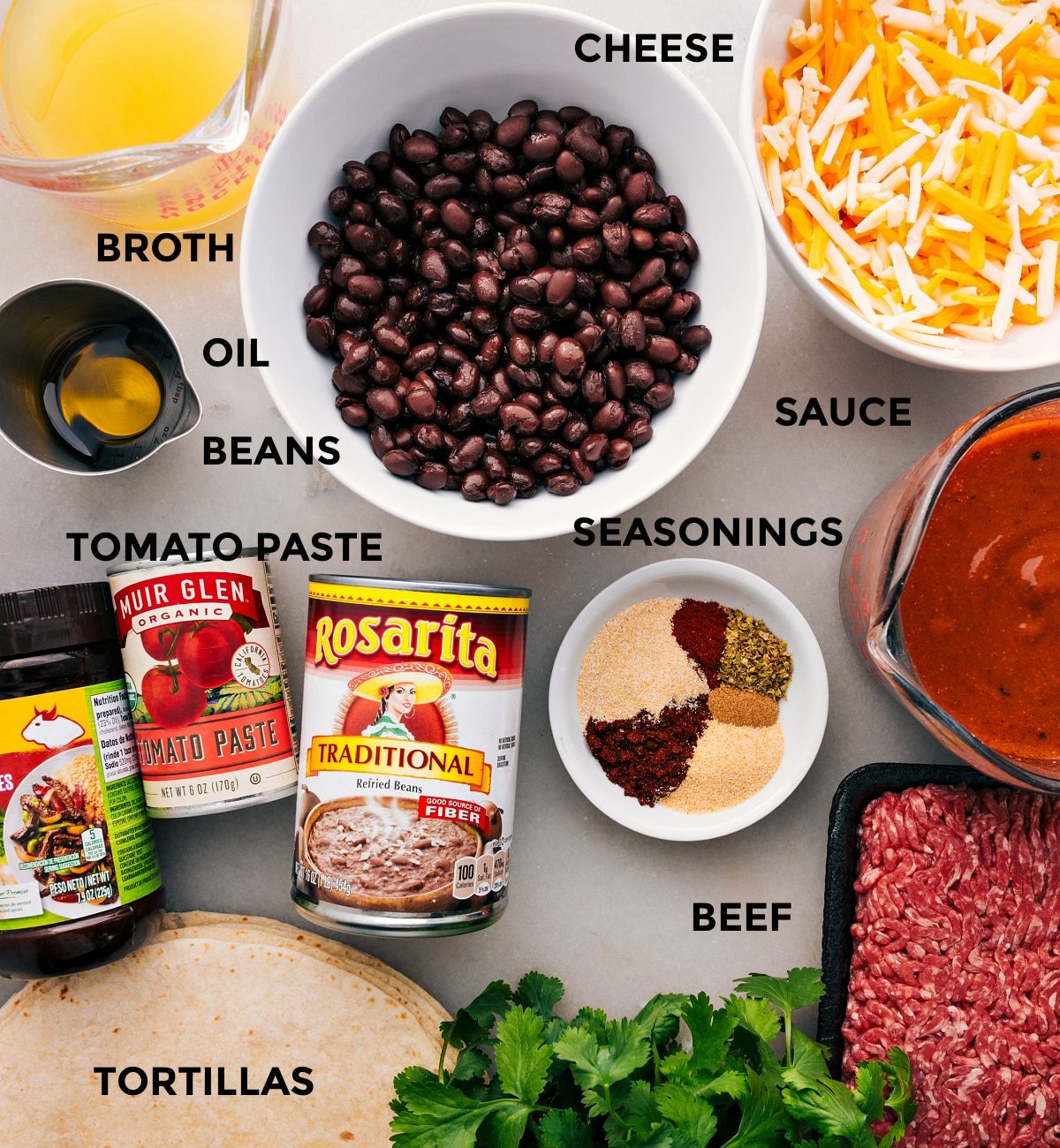 Ingredients prepped for straightforward assembly—broth, cheese, beans, sauce, seasonings, beef, tomato paste, and tortillas.