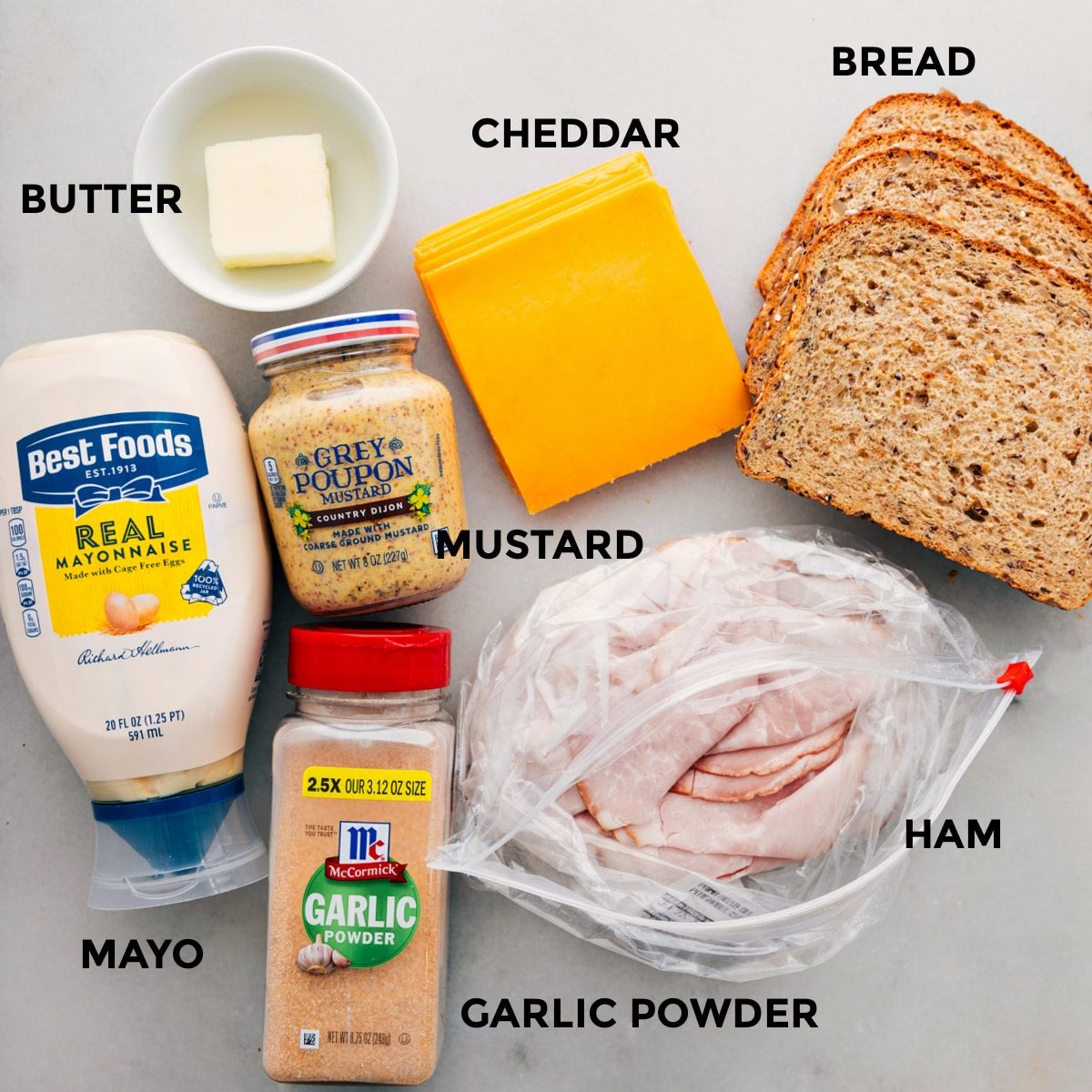 All the ingredients in this recipe including the meat, bread, cheddar, mustard, butter, mayo, and garlic powder prepped out for straightforward assembly.