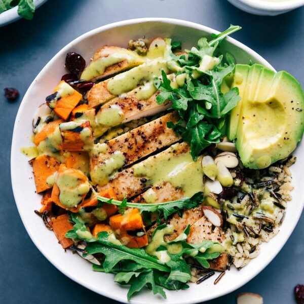 Chicken and wild rice in a bowl, featuring well-cooked, sliced chicken and creamy sauce poured on top, creating a healthy and satisfying meal.