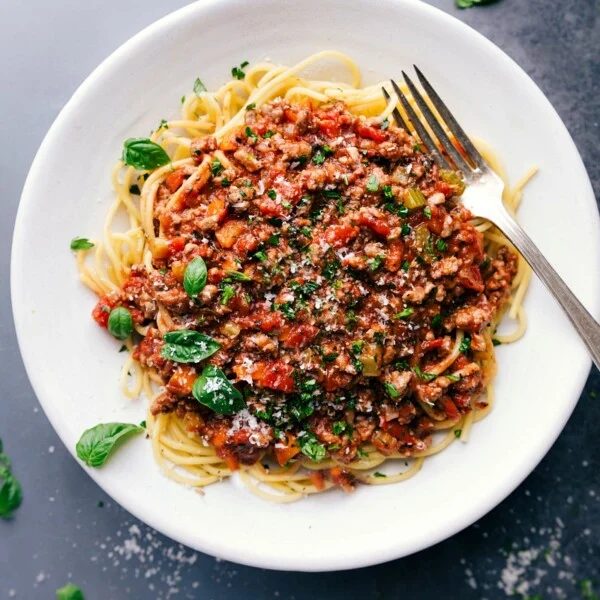 Savory and satisfying turkey bolognese on a bed of spaghetti, topped with fresh herbs.