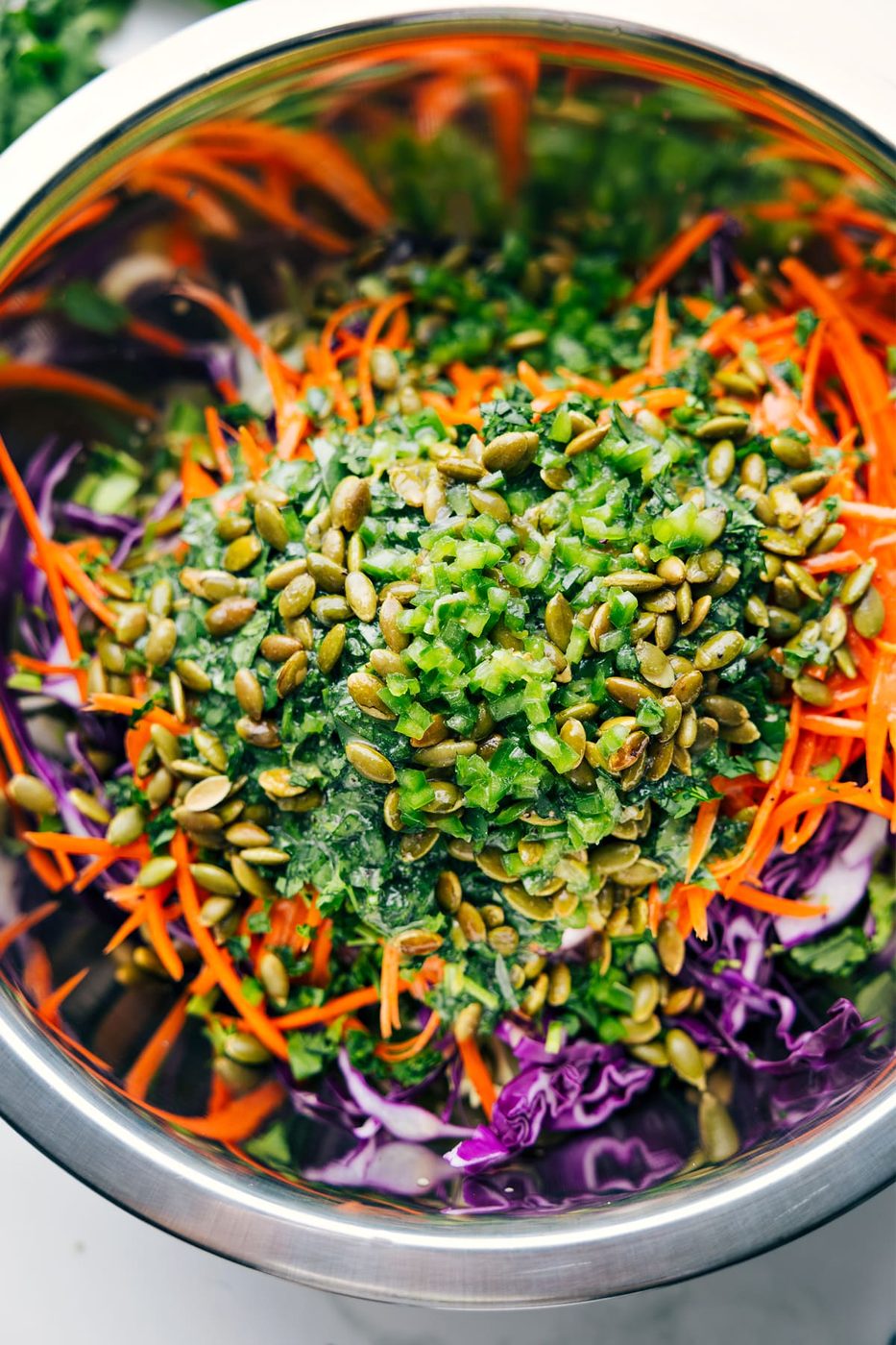 Healthy Slaw ingredients in a large bowl with the dressing poured over the top, ready to be tossed together.