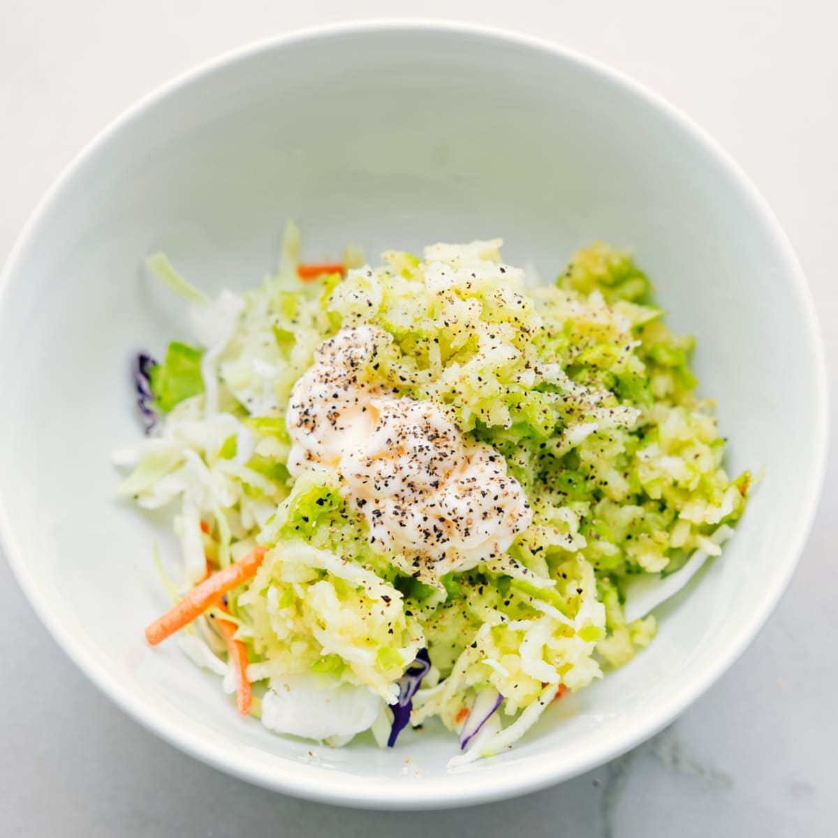 The coleslaw mix ingredients being added to a bowl for these healthy turkey wraps.
