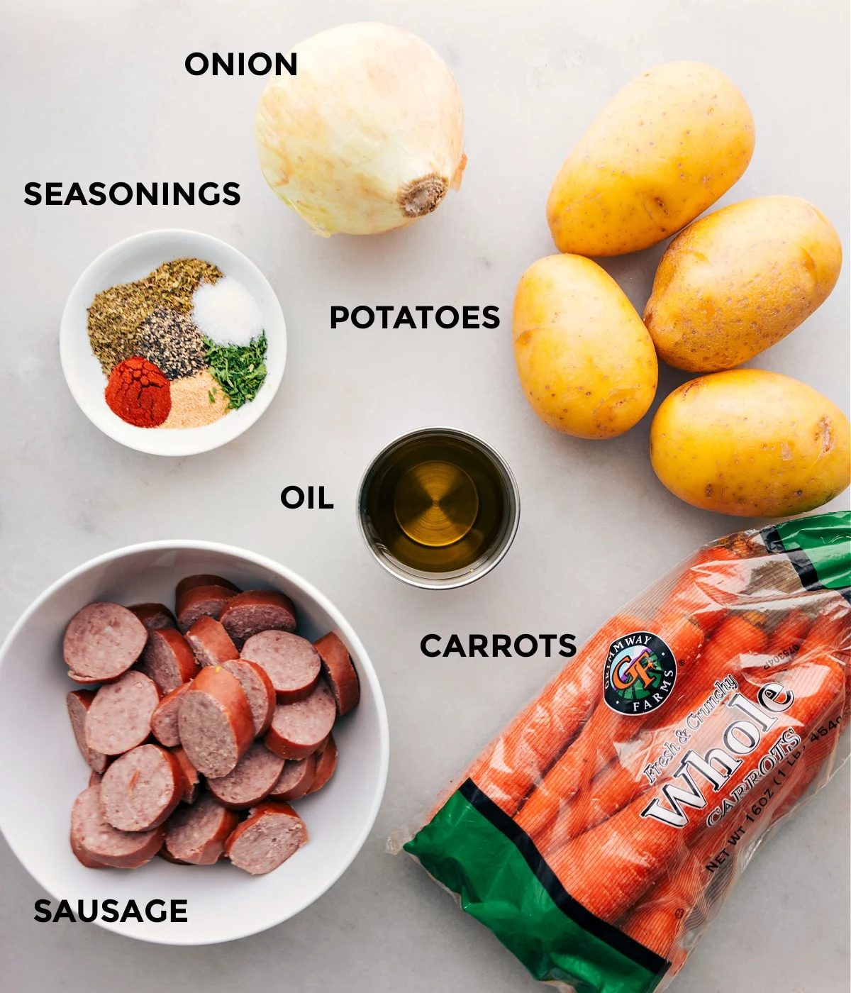 All the ingredients in this recipe including sausage, seasonings, onion, potatoes, and carrots being prepped for straightforward assembly.