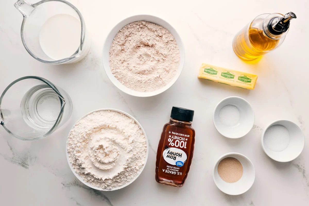 Ingredients in this recipe prepped out for straightforward assembly including milk, water, flour, honey, yeast, salt, sugar, butter, and oil.