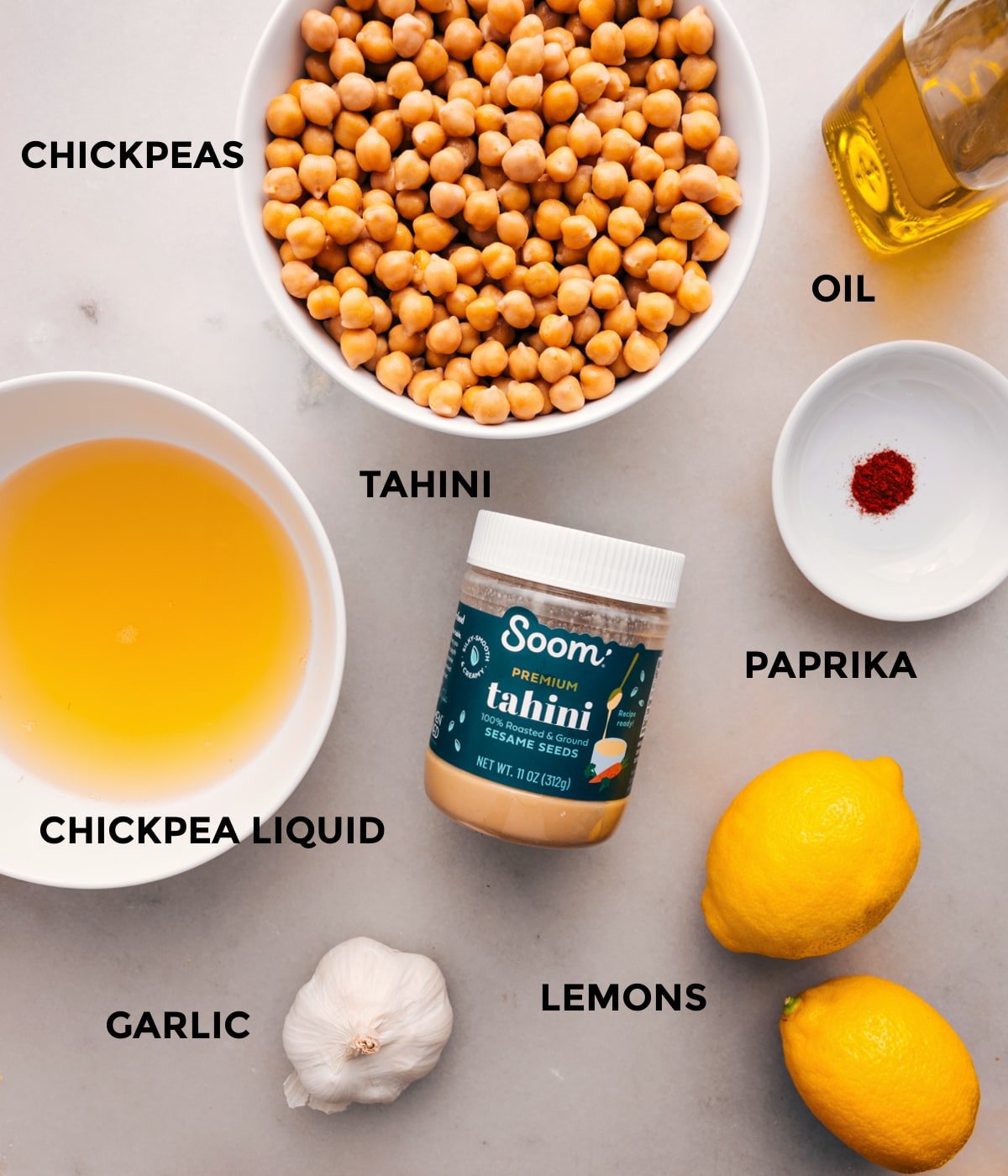 All the ingredients prepped for straightforward assembly, including oil, chickpeas, tahini, paprika, lemons, and garlic.