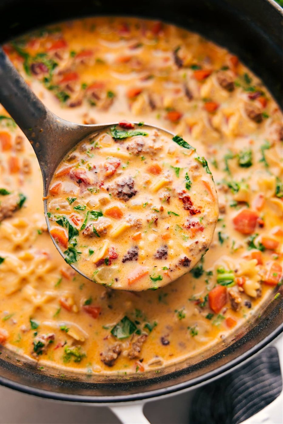 Sausage pasta soup with vegetables, sun-dried tomatoes, pasta, and creamy broth.