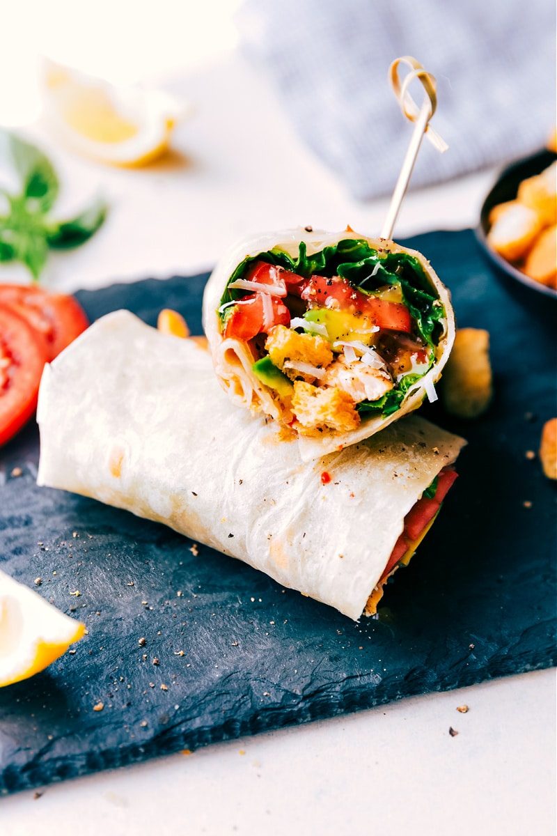 Italian recipes wrap filled with chicken, lettuce, tomatoes, avocado, Parmesan, croutons, and dressing.