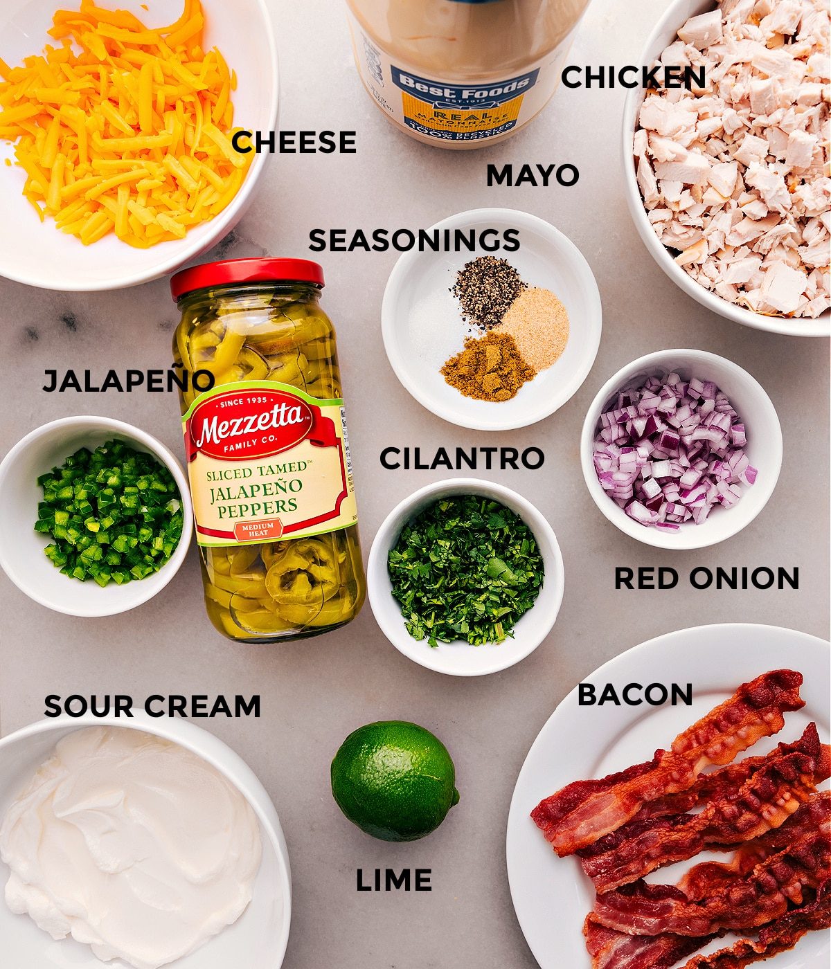 All the ingredients for this recipe are prepped for straightforward assembly, including cheese, mayo, eggs, seasonings, meat, and sour cream.