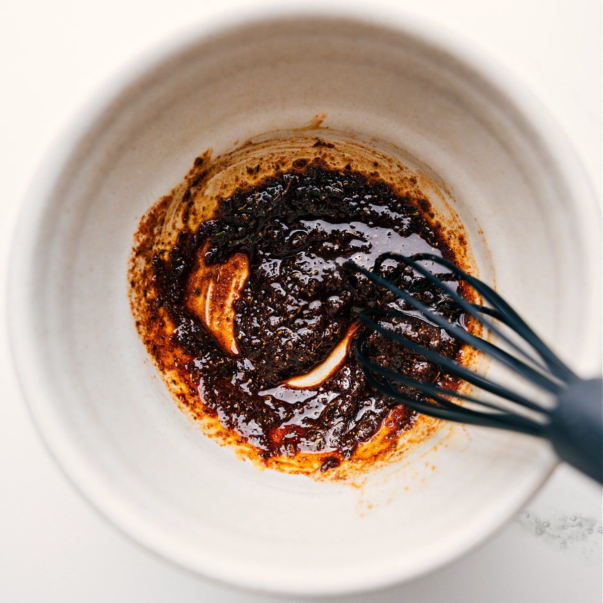 Jerk Chicken marinade ingredients being whisked together in a bowl.