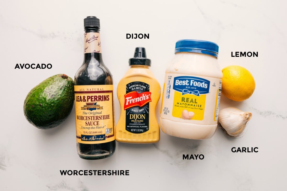 All the ingredients in this kale and avocado salad prepped out for straightforward assembly including the avocado, worcestershire, dijon, mayo, lemon, and garlic.