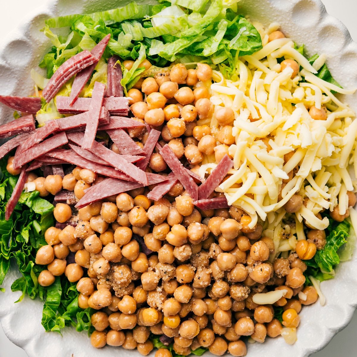 The salad ingredients in a bowl with dressing, ready to be tossed.
