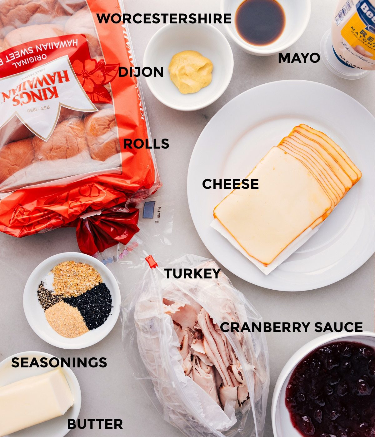 All the ingredients in this recipe prepped for straightforward assembly including the rolls. dijon, Worcestershire, mayo, cheese, turkey, cranberry sauce, and butter.