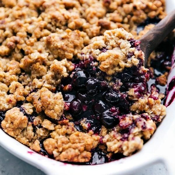 Freshly baked dessert with a spoonful being taken out, revealing its satisfying and fruity interior, warm and inviting.