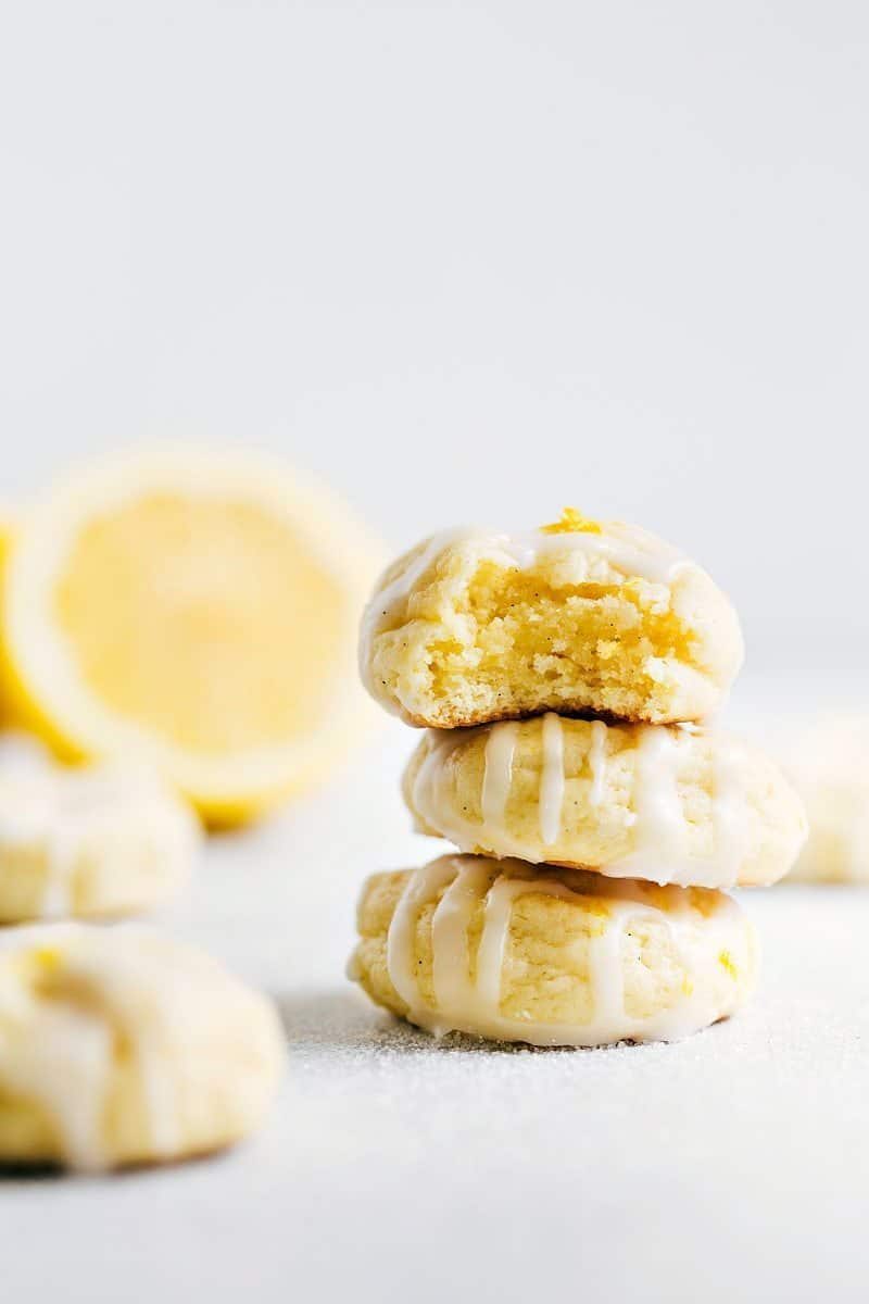 A stack of three lemon cheesecake cookies topped with a satisfying frosting with a bite taken from the top cookie.