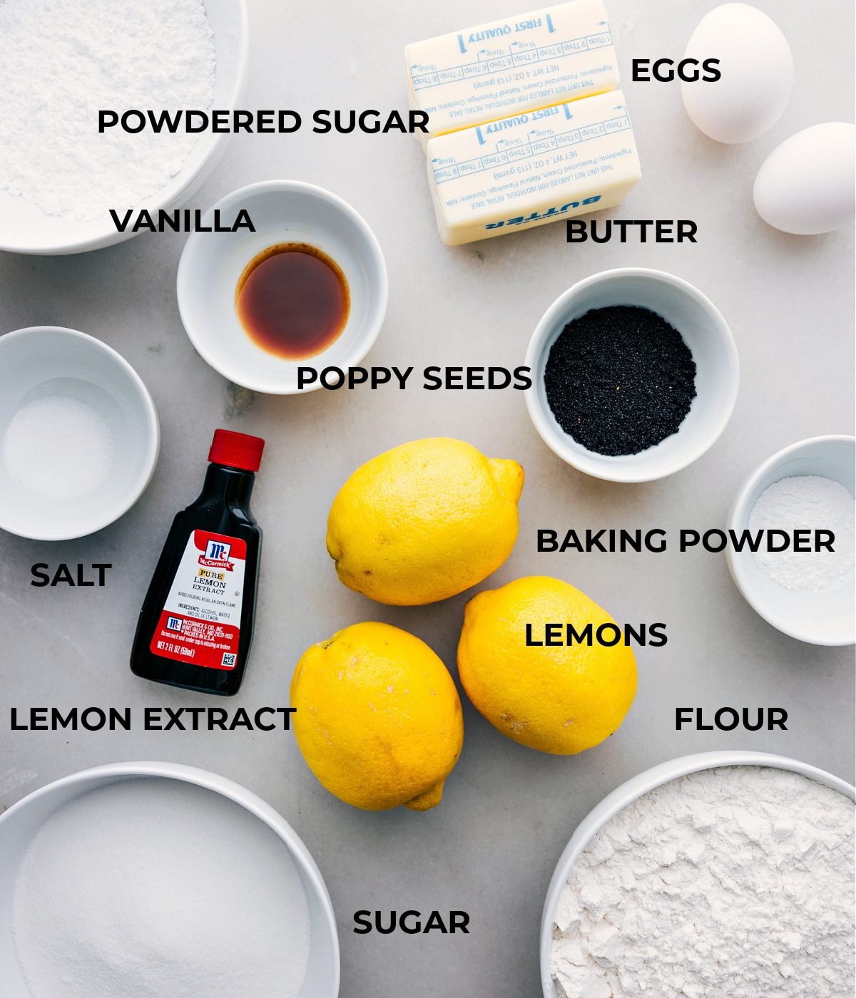 All the ingredients in this recipe are prepped and ready for straightforward assembly: eggs, powdered sugar, vanilla, poppy seeds, baking powder, lemons, lemon extract, and salt.