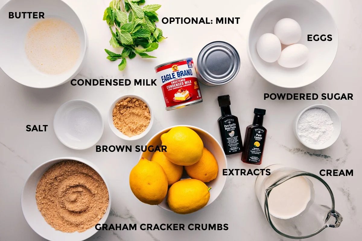 All the ingredients in this recipe prepped out for straightforward assembly including the butter, salt, graham cracker crumbs, condensed milk, extracts, cream, powdered sugar, eggs, and mint.